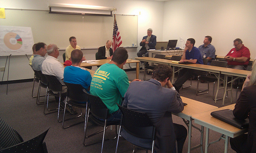 Iowa producers and residents discuss the impact the next farm, food and jobs bill can have on rural economies with Congressman Braley (in yellow shirt at head of table) and Deputy Under Secretary O’Brien (next to flag).