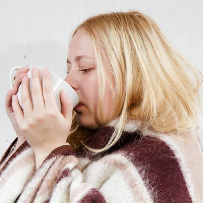 A woman drinks hot water and honey to ward off the flu.