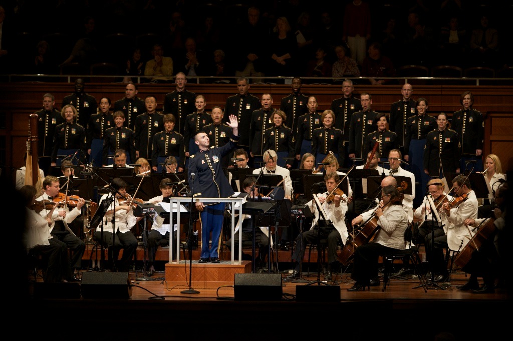 Captain Leonoel A. Peña, conductor of The Army Field Band's Soldiers' Chorus, waves to acknowledge veterans in the audience during a performance with the Nashville Symphony Orchestra.
