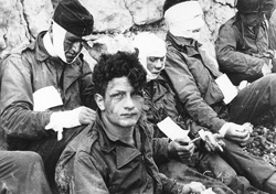 Normandy Invasion, June 1944 Wounded men of the 3rd Battalion, 16th Infantry Regiment, 1st Infantry Division, receive cigarettes and food after they had stormed 'Omaha beach on 'D-Day', 6 June 1944., Army Signal Corps Collection in the U.S. National Archives. SC 189910