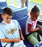 Two kids buckling up on bus.