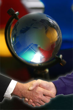 Two men's hands shaking in front of a globe.