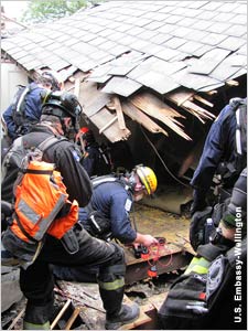 Rescuers peering into hole in building (U.S. Embassy Wellington)