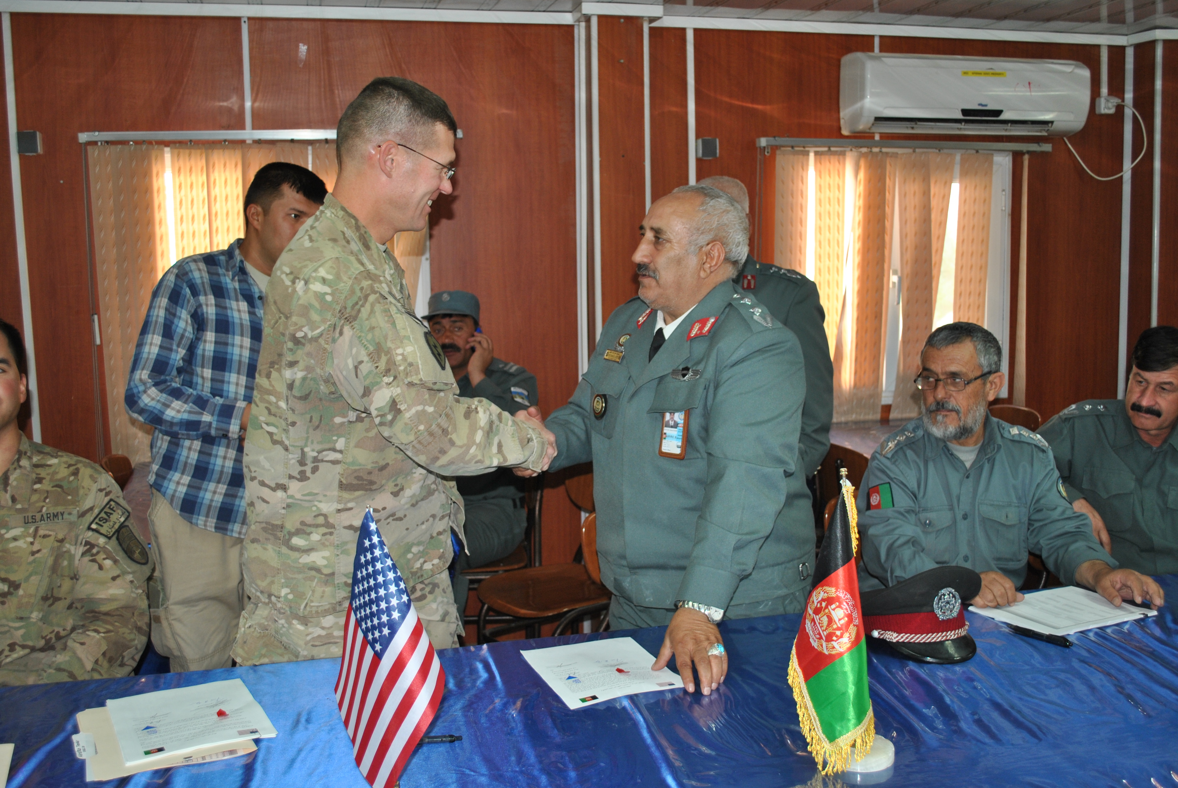 US Army Col. Keith Detwiler, Regional Support Command-West commander and Afghan National Police Col. Fazi Ahmad Khalili, Adraskan National Training Center commander, shake hands after transitioning the training center to Afghan control in a ceremony held at the site Sept. 29. (US Navy photo by LT. David P. Varney, RSC-W/NTM-A PAO)