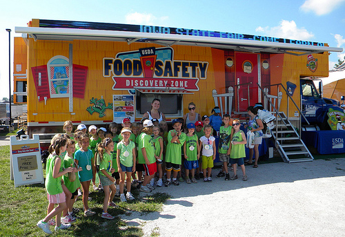 A school group poses in front of the Food Safety Discovery Zone after learning to Clean, Separate, Cook, and Chill.