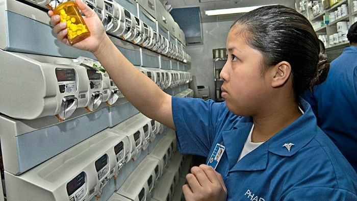A Hospital Corpsman uses an automatic pill dispenser to refill a patient's prescription