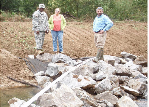 Earth Team Volunteer Sgt. Patrick Bower, Soil Conservationist Janet Coleman and District Conservationist Kevin Hart inspect a streambank protection jetty.