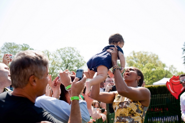 First Lady Michelle Obama lifts a baby at Easter Egg Roll