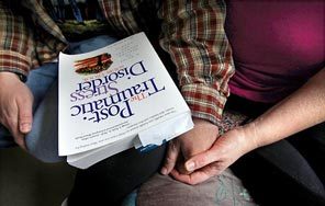 Paxton holds her husband's hand as he sits with a copy of "The Post-Traumatic Stress Disorder Sourcebook" in his lap. 