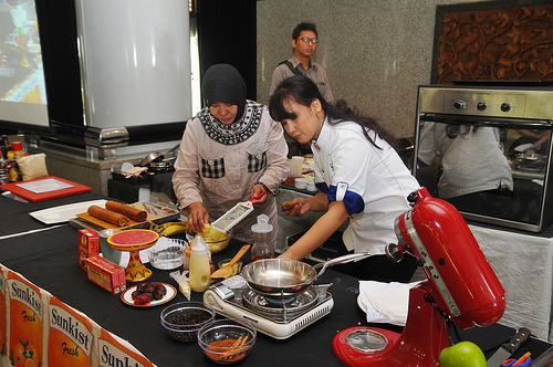 Chef Ucu Sawitri invited one of the participants to work with her to prepare an "Apple Banana Roll" recipe using dehydrated potato flake, Washington apples, California raisins, and Washington apple juice.