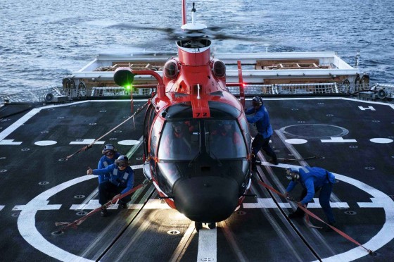 Coast Guard Cutter Bertholf flight deck crewmmbers tie down an MH-65 Dolphin helicopter arriving from Air Station Los Angeles to the deck to secure for sea transit. U.S. Coast Guard photo by Petty Officer 1st Class Timothy Tamargo.