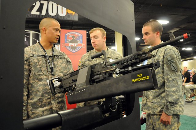 Spc. Jose Palomino, Spc. James Cobb, and Spc. Kenneth Waller, look at a modified M240 machine gun that is mounted in a mock-up door frame from a CH-47 Chinook helicopter during the 2011 Army Aviation Association of America's Annual Professional Forum and Exposition in Nashville, Tenn. The M240's turret mount has been modified to ensure the weapon doesn't hit the window frame