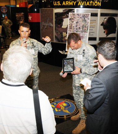 Lt. Col. Craig Unrath, deputy director of the Directorate of Simulations, and Maj. Lee Ambrose, commander A Company, 1st Battalion, 145th Aviation Regiment, explain the Army Learning Concept 2015 at the U.S. Army Aviation Center of Excellence Booth during the Army Aviation Association of America professional forum in Nashville, Tenn.