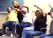 Veterans sit in a circle of chairs, stretching arms upward