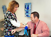 Phlebotomist Tracey Bach helps VAPHS Deputy Director David Cord donate a small amount of blood as part of his participation in the MVP.