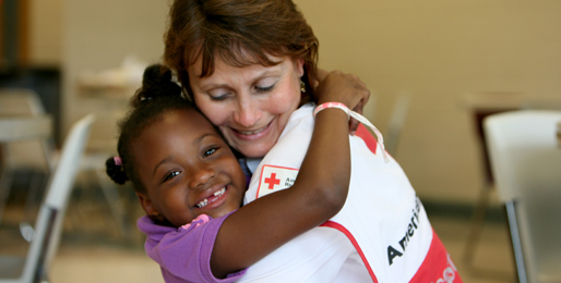 Red Cross volunteer hugging a little girl