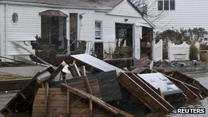 Furniture and other items left after being damaged during superstorm Sandy stand on a flooded street during snowfall in New York