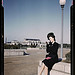 Woman putting on her lipstick in a park with Union Station behind her, Washington, D.C. (LOC)