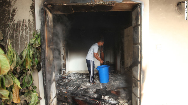 A man stands in part of the burned-out compound Wednesday. 