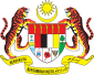 Shield showing symbols of the Malaysian states with a star and crescent above it and a motto below it supported by two tigers