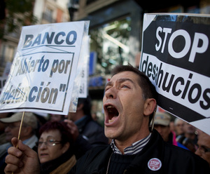 A demonstrator shouts during a protest against housing evictions in Madrid last month. The sign to his right reads, "Stop evictions."