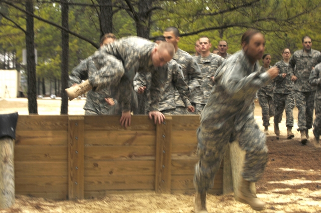 Recruits hop over a barrier at the "Fit to Win" confidence course.