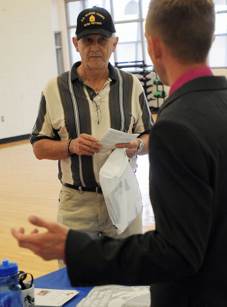 Russell Easley of Allentown, a U.S. Marine Corps. veteran, listens as Jonathan Tompkins, of the Keystone Wounded Warriors, explains how his organization helps veterans find jobs and with financial hardships, during a job fair hosted by Congressman Charlie Dent on Saturday at the Lehigh Carbon Community College gymnasium in Schnecksville.