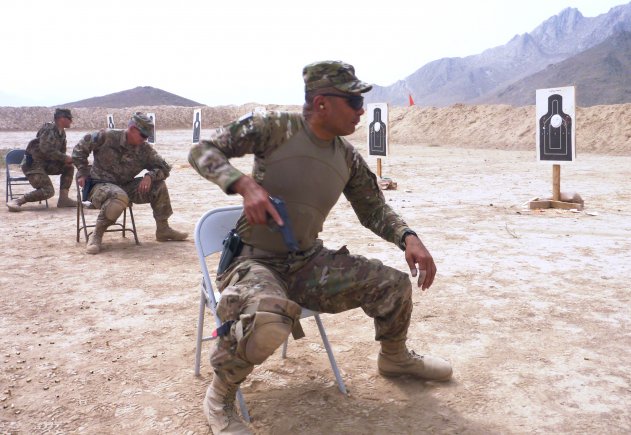 Col. Richard Wilson, commander, Regional Support Command-South, and others react upon range instruction to vacate their chairs and quickly turn forward to position themselves on a knee to fire down range during Quick Reaction Drill Training. (Photo by Jon Connor)