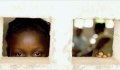 Girl speering in a small window (USAID)