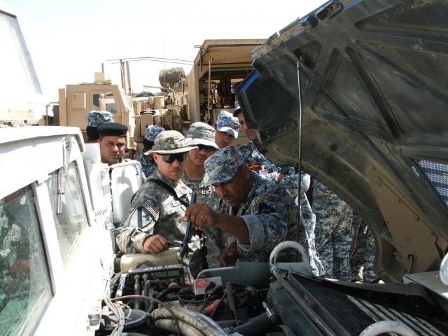 BAGHDAD- Staff Sgt. Robert Mills (center), a mechanic with 1st Battalion, 82nd Field Artillery Regiment, 1st Brigade Combat Team, 1st Cavalry Division, works with Iraqi National Police during a humvee maintenance course held as part of an ongoing effort to train Iraqi Security Forces.  The 3rd Brigade, 1st Iraqi National Police Division purchased 75 new humvees to replace pick-up trucks used as service vehicles in their sector of Baghdad.