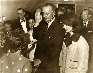 Jackie Kennedy Standing Next to Lyndon Johnson, with Right Hand in the Air and Hand on Book, Others Looking On