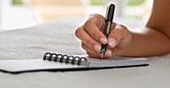 Image: Woman writing in journal (© AAGAMIA/Getty Images)