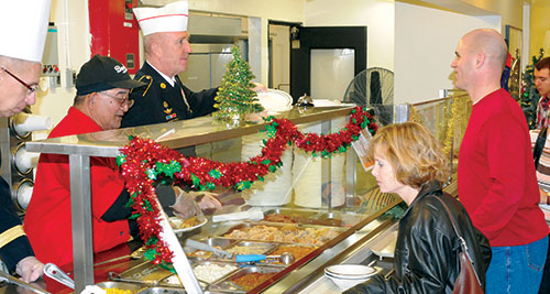 Photo of Command Sgt. Maj. Roger P. Blackwood, preparing a plate for Col. and Mrs. Ryan LaPorte