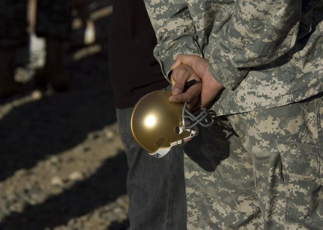 FORT BLISS, Texas (December 28, 2010) A Fort Bliss Soldier waits for autographs from University of Notre Dame Fighting Irish football players at Abernethy Obstacle Course on Bliss' main post, Dec. 28. Notre Dame players and their counterparts from the University of Miami visited Bliss to meet with members of Team Bliss and to get a taste of the training and lifestyle of today's Army. Notre Dame and Miami will face off in the 2010 Hyundai Sun Bowl Dec. 31. Photo by David Poe.