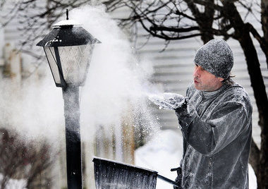 Daniel Yeager of the Los Angeles-based Snow Business Hollywood blows a fine layer of cellulose against a lamppost to create the impression of a fresh winter scene along N. Jefferson Street in Mexico during an advertising photo shoot for AT&T.  John Berry / The Post-Standard
