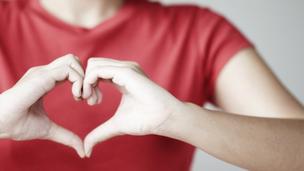 A woman shaping a heart sign with her hands