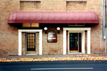 Single awnings should not be set over more than one door or window bay.  A separate shed awning with a canvas or acrylic covering would be more appropriate over each of these openings. Photo: NPS files.