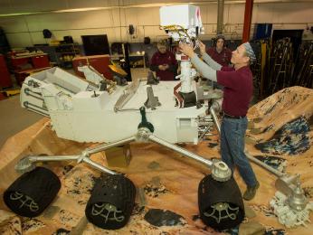 On Saturday morning, Jan. 19, 2013, at Joint Base Anacostia Bolling (JBAB) in Washington, Steve LaDrew, with Capitol Exhibit Services, adjusts the Mastcam on a replica of the Mars Curiosity Rover.