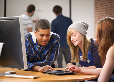 A group of students using a tablet to complete an assignment in class; ThinkStock.com 