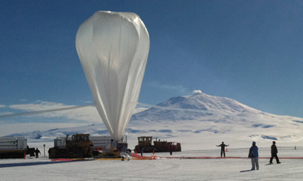 The balloon, ready to launch, dwarfs launch crew standing on the ice field.