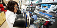 A woman in a lab coat works in a laboratory assembling a lithium Ion battery.