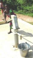 A Ghanaian woman pumps water at a borehole built by USAID