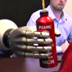 Photo of a woman controlling a robotic arm to grasp a bottle.