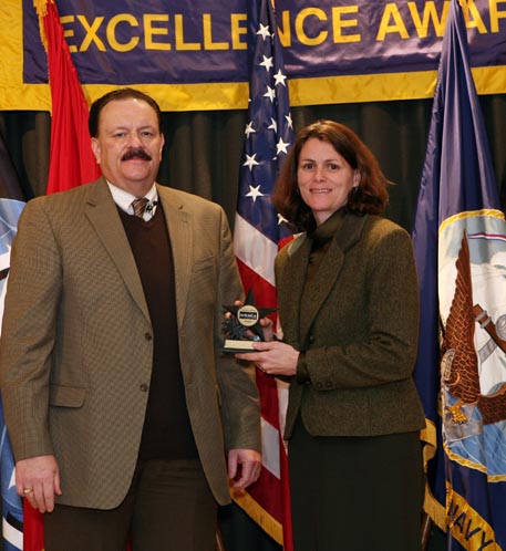 Naval Sea Systems Command Executive Director Brian Persons presents the NAVSEA Excellence Award to Nancy Haymes, an Acquisition Engineering Agent from Naval Surface Warfare Center Dahlgren Division (NSWCDD) at a ceremony held in Washington D.C. Dec. 11.  Haymes was one of 37 NSWCDD employees serving on teams honored for excellence in their contributions to the Navy.