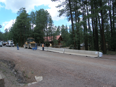 Apache County crews work to install concrete barriers to protect a home in Alpine. 