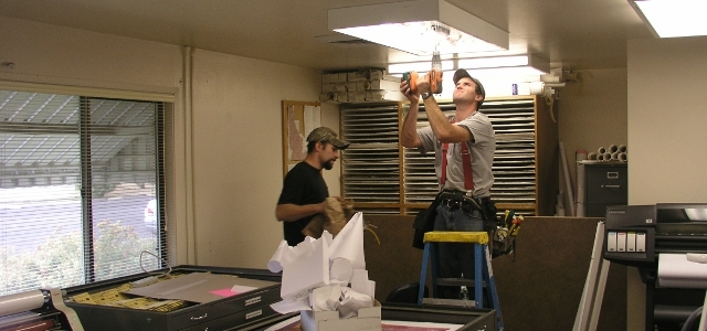 Electricians working on fluorescent light fixture
        