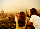 Two women point to European city landscape