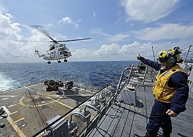 Boatswain's Mate 3rd Class Kristin Butts, a landing signalman aboard the Arleigh Burke-class guided-missile destroyer USS Dewey (DDG 105), signals an AS-332 Super Puma helicopter during a vertical replenishment with the Military Sealift Command dry cargo and ammunition ship USNS Washington Chambers (T-AKE 11). USS Dewey is deployed to the U.S. 7th Fleet area of responsibility conducting maritime security operations.  U.S. Navy photo by Mass Communication Specialist 3rd Class Joshua Keim (Released)  120124-N-VH839-038