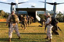 Sergeants James T. Wilkins, left, and Kevin J. Van Arsdale, right, guide Marines as they exit an MV-22B Osprey Jan. 29 at the Central Training Area near Camp Hansen. Ospreys transported Marines into the training area to begin the culminating event of the III Marine Expeditionary Force Headquarters Group-sponsored corporals course. Wilkins and Van Arsdale are course instructors. 