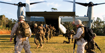 Sergeants James T. Wilkins, left, and Kevin J. Van Arsdale, right, guide Marines as they exit an MV-22B Osprey Jan. 29 at the Central Training Area near Camp Hansen. Ospreys transported Marines into the training area to begin the culminating event of the III Marine Expeditionary Force Headquarters Group-sponsored corporals course. Wilkins and Van Arsdale are course instructors. 